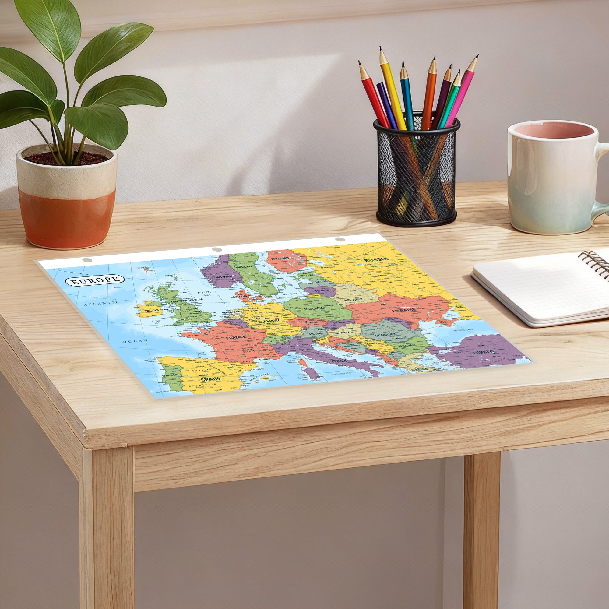 Desk with a map of Europe, pencils, a mug, and a plant.